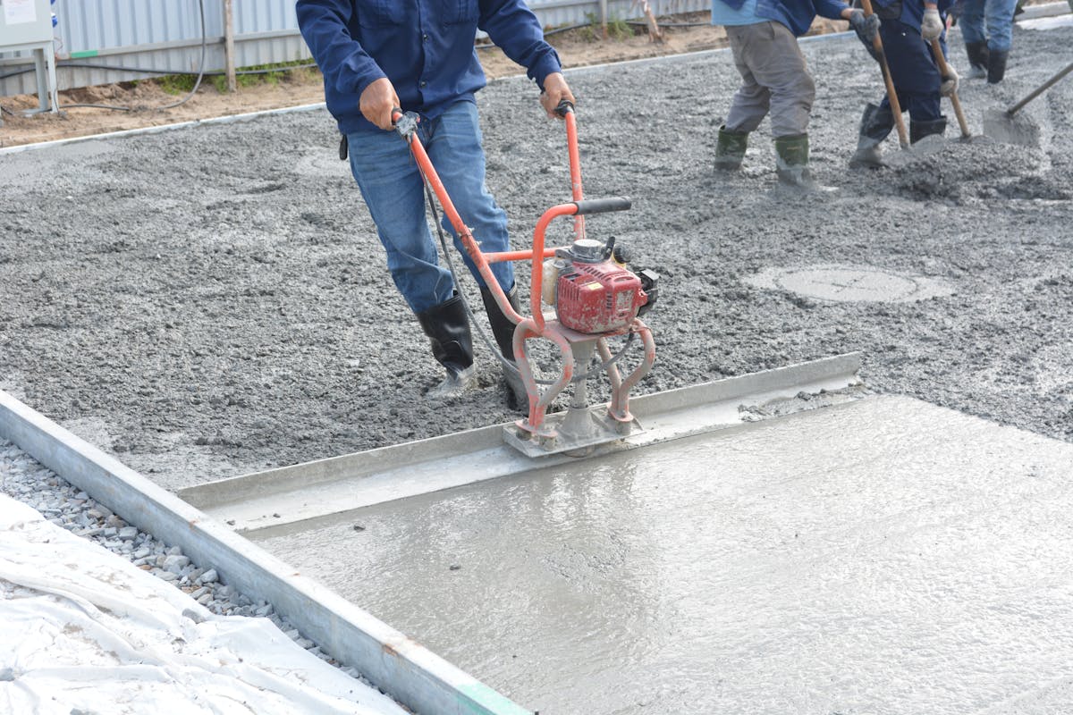 Workers smoothing concrete subfloor during floor preparation in Washington UT